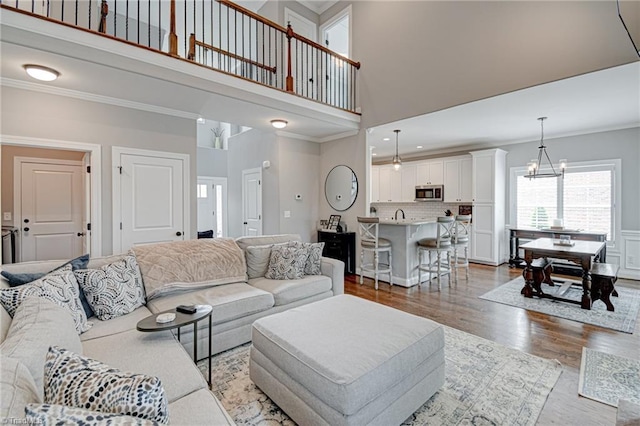 231 Plumstead Ln, Clemmons, NC 27012 - living room featuring ornamental molding, wood finished floors, a chandelier, and a towering ceiling