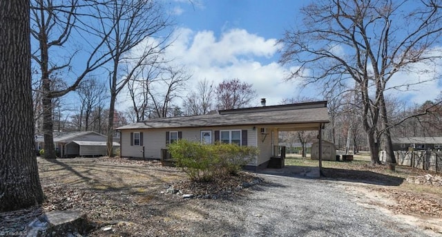 view of front of house featuring a carport, driveway, a storage unit, and an outdoor structure