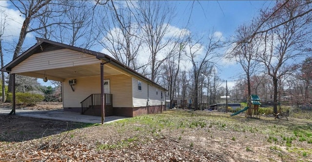 view of home's exterior with a wall mounted air conditioner, crawl space, a carport, and a playground