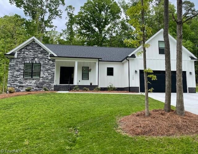 modern inspired farmhouse featuring a porch, a front yard, driveway, board and batten siding, and an attached garage