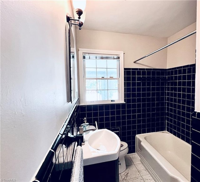 508 Audubon Dr, Greensboro, NC 27410 - bathroom with vanity, tile walls, marble look tiles, tub / shower combination, and wainscoting