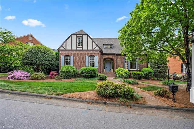 tudor house featuring a front lawn and brick siding