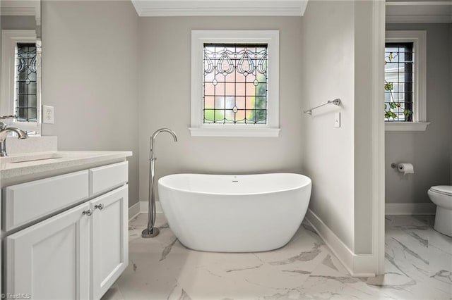 bathroom with baseboards, toilet, a freestanding tub, vanity, and marble finish floor