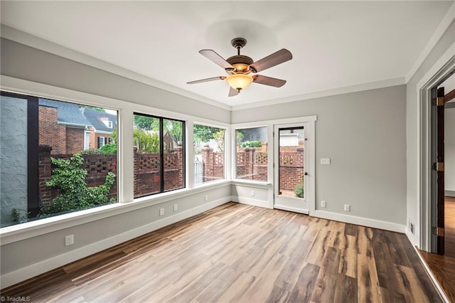 unfurnished sunroom with crown molding, wood finished floors, and baseboards