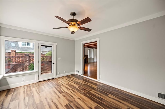 empty room featuring wood finished floors, a ceiling fan, visible vents, and baseboards