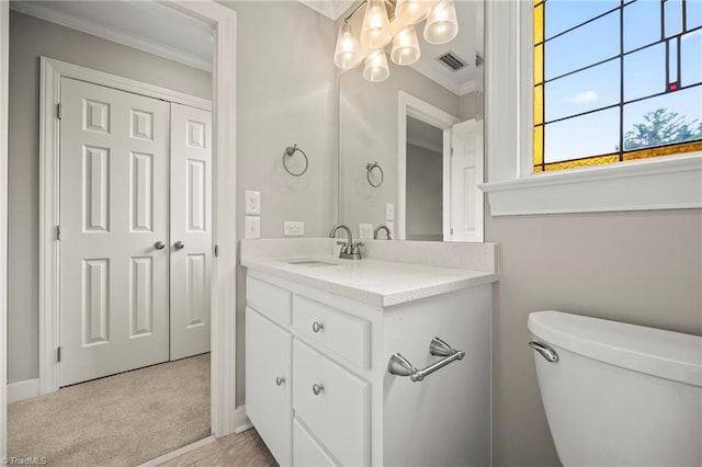 half bathroom with a chandelier, vanity, crown molding, toilet, and visible vents