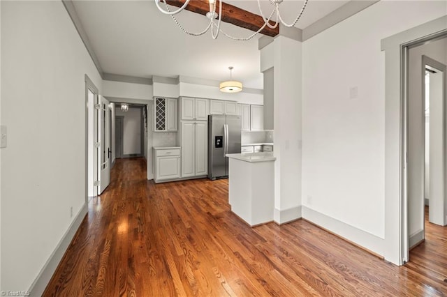 kitchen with gray cabinets, stainless steel fridge, dark wood-style flooring, and light countertops