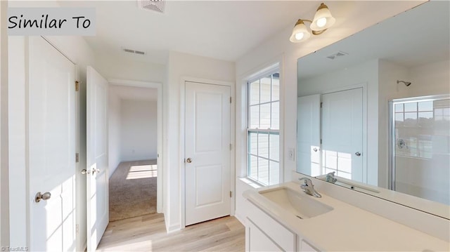 bathroom featuring wood-type flooring, vanity, and a shower with shower door