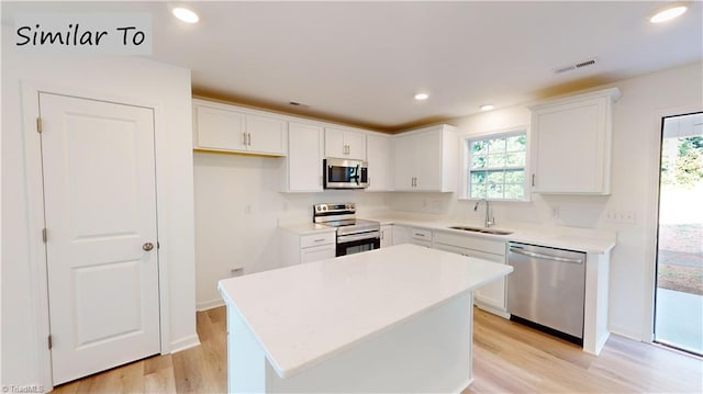 kitchen featuring a wealth of natural light, a center island, white cabinetry, and appliances with stainless steel finishes