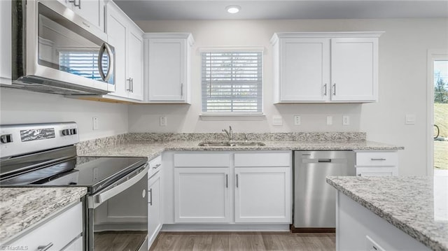 821 Merriweather Dr, King, NC 27021 - kitchen featuring appliances with stainless steel finishes, a sink, white cabinetry, light wood-style floors, and light stone countertops