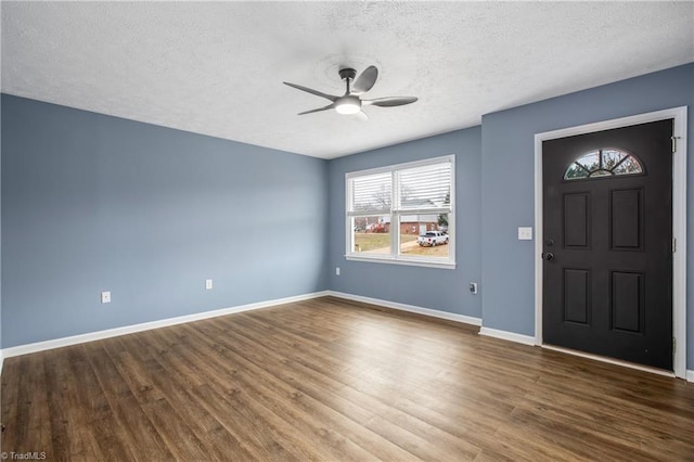 foyer entrance featuring a textured ceiling, dark wood-type flooring, and ceiling fan