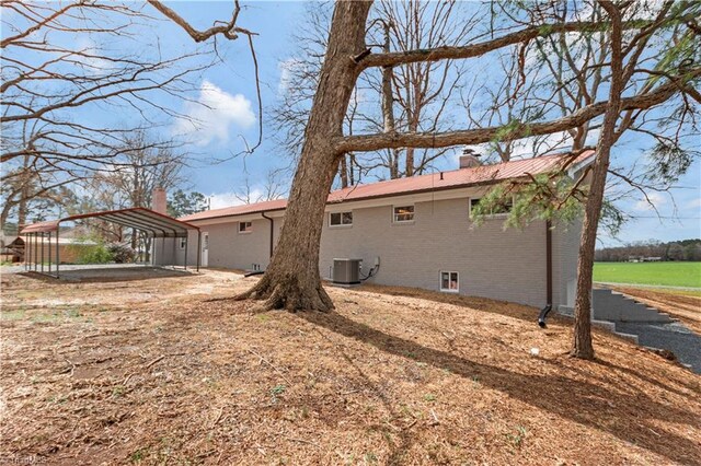 4566 Fork Rd, Norwood, NC 28128 - view of home's exterior featuring a carport, a chimney, brick siding, metal roof, and cooling unit