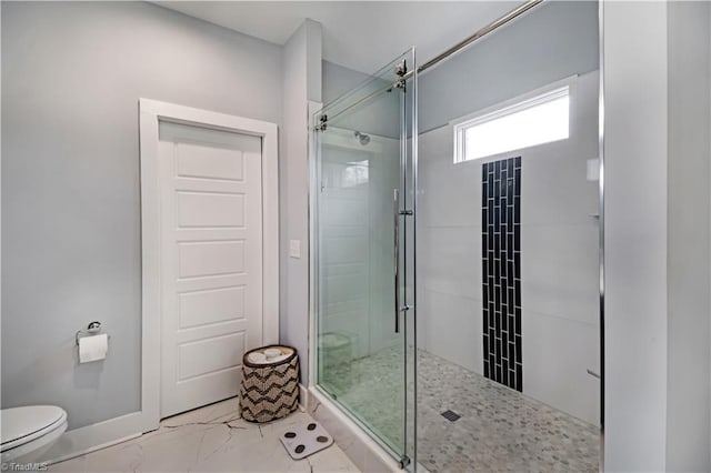 bathroom featuring a shower with shower door and toilet