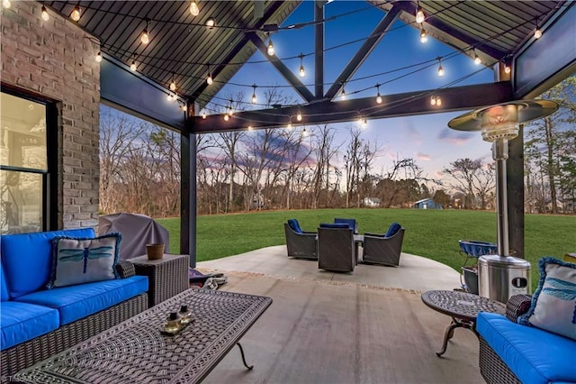 patio terrace at dusk with area for grilling, outdoor lounge area, and a lawn