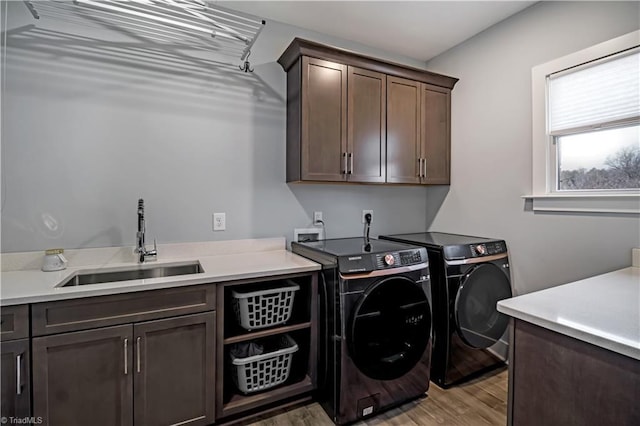 laundry room featuring cabinets, sink, washing machine and clothes dryer, and light wood-type flooring