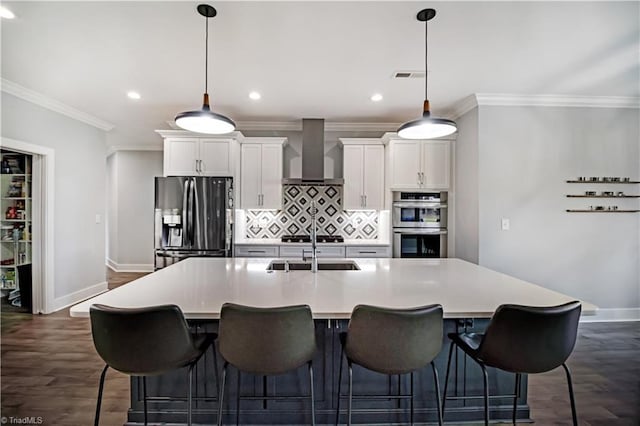 kitchen featuring a spacious island, appliances with stainless steel finishes, white cabinets, and wall chimney exhaust hood