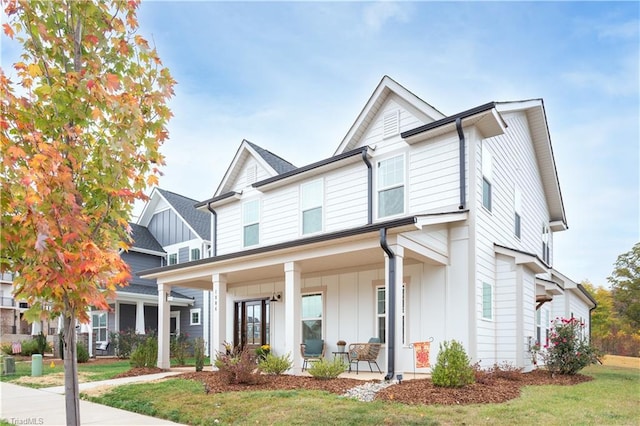 view of front of house featuring a porch, a front lawn, and board and batten siding