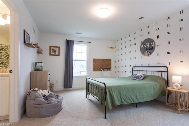 bedroom with ensuite bath, light colored carpet, and baseboards