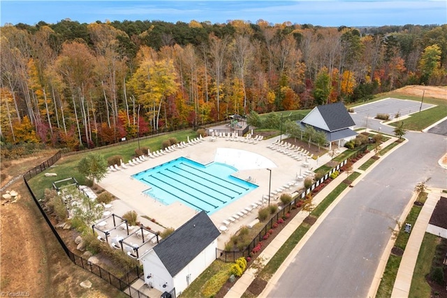 pool with fence, a patio area, and a wooded view