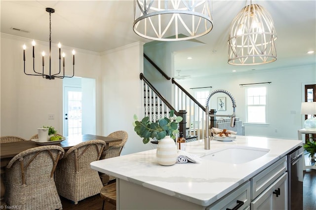 kitchen featuring ornamental molding, a kitchen island, visible vents, and a sink