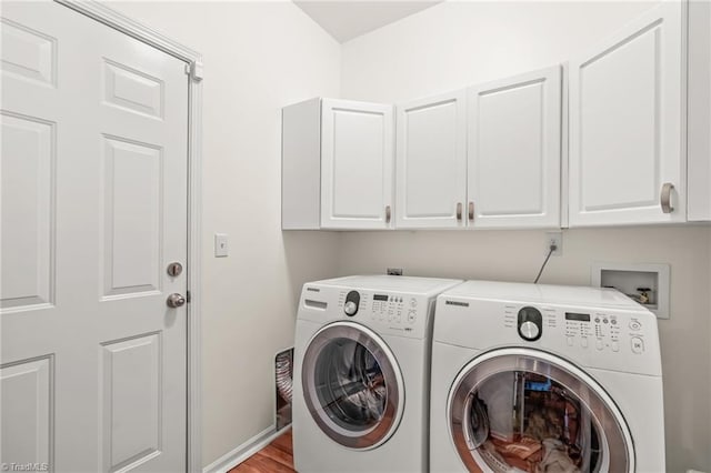 washroom with cabinets, light wood-type flooring, and washing machine and dryer