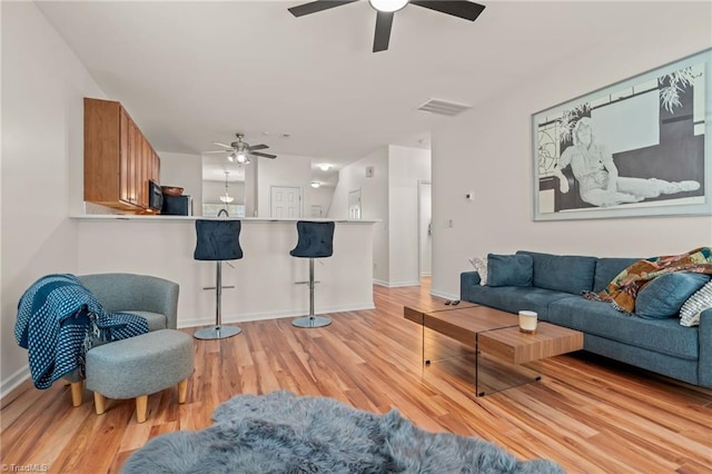 living room featuring ceiling fan and light hardwood / wood-style floors