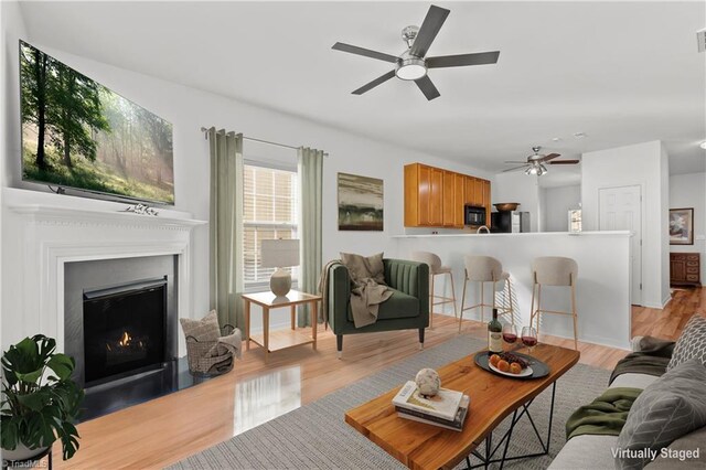 living room featuring a wealth of natural light, ceiling fan, and light wood-type flooring