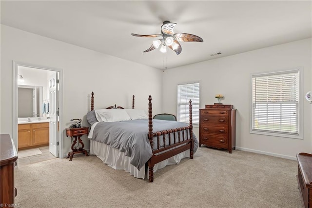 bedroom with multiple windows, light colored carpet, ceiling fan, and ensuite bathroom