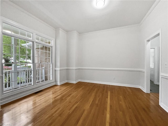 spare room with crown molding, wood finished floors, and baseboards