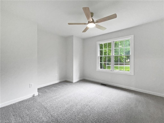 carpeted spare room featuring ceiling fan and baseboards
