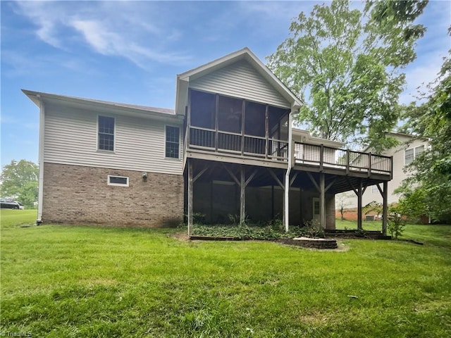 rear view of property featuring a sunroom, a lawn, a deck, and brick siding