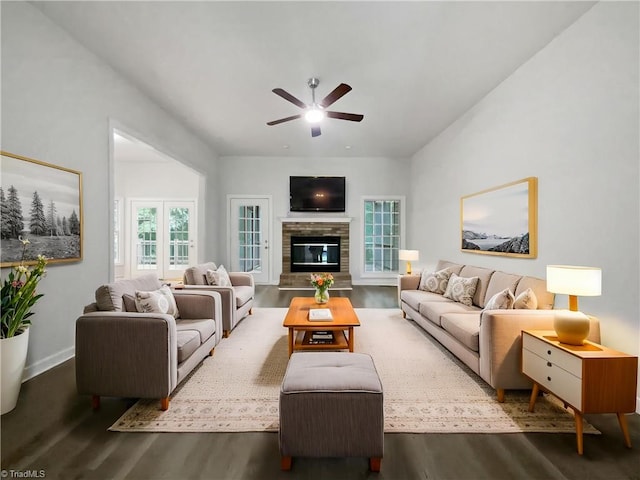 living room with wood finished floors, a ceiling fan, a fireplace, and baseboards