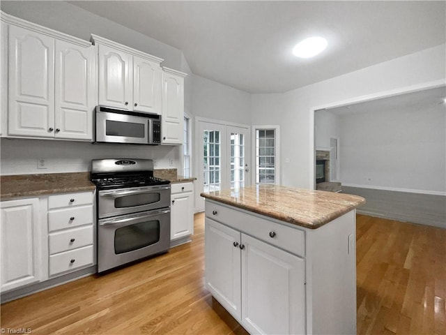 kitchen with stainless steel appliances, light wood-type flooring, white cabinetry, stone countertops, and french doors