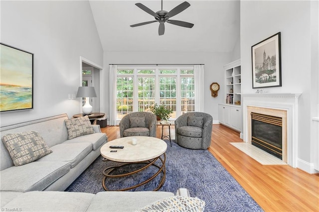 living room featuring hardwood / wood-style flooring, ceiling fan, high vaulted ceiling, and built in shelves