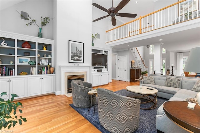 living room with light hardwood / wood-style flooring, high vaulted ceiling, and ceiling fan