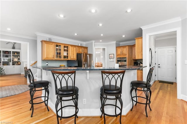 kitchen featuring a breakfast bar, light wood-type flooring, kitchen peninsula, and appliances with stainless steel finishes