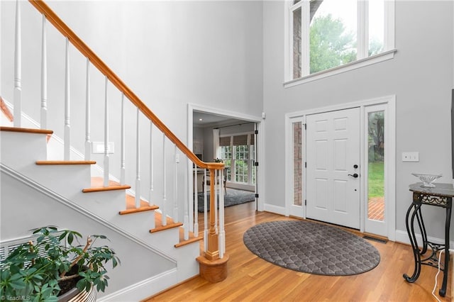 entrance foyer featuring light wood-type flooring, a towering ceiling, and a wealth of natural light