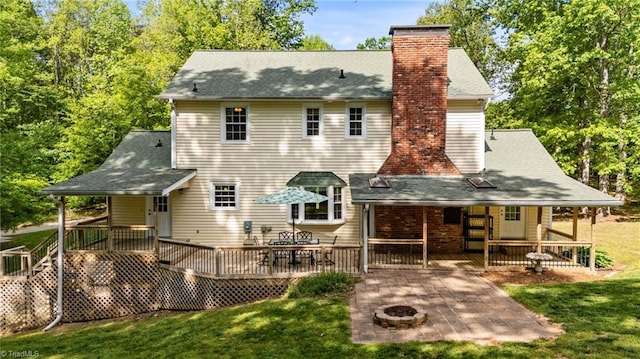 rear view of house with a patio, a chimney, a yard, and a fire pit