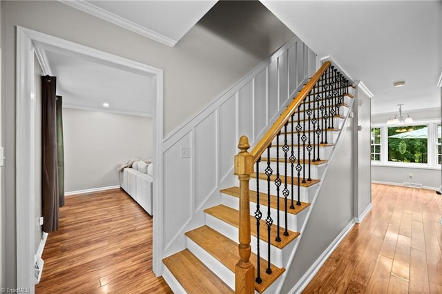 staircase featuring crown molding, baseboards, wood finished floors, and a notable chandelier