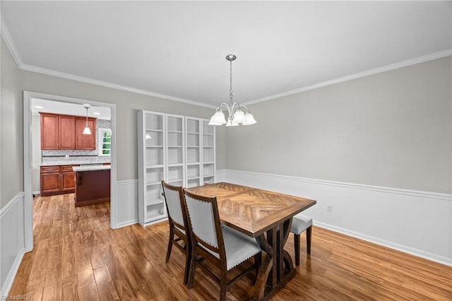dining room with crown molding, baseboards, wood finished floors, and a chandelier