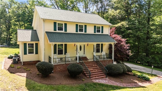 view of front facade featuring a shingled roof, a front lawn, stairway, central AC unit, and covered porch