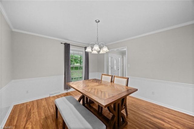dining area with crown molding, a chandelier, wood finished floors, and visible vents