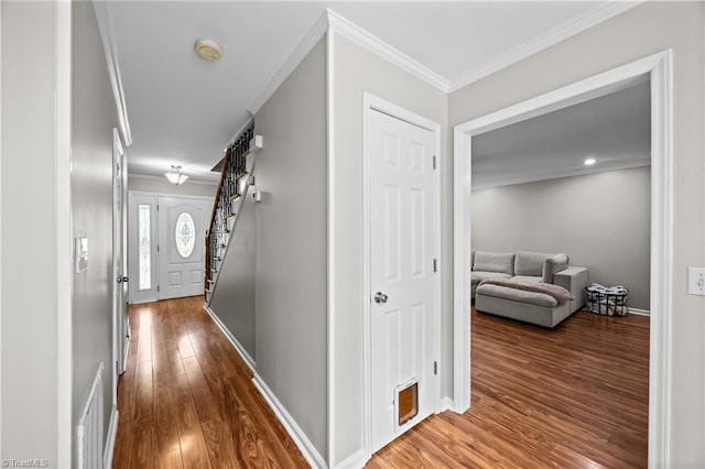 hallway featuring stairs, baseboards, ornamental molding, and wood finished floors
