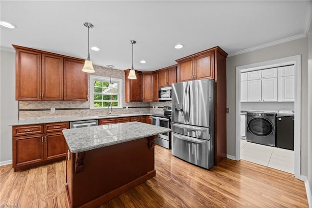 kitchen featuring tasteful backsplash, a sink, separate washer and dryer, ornamental molding, and stainless steel appliances