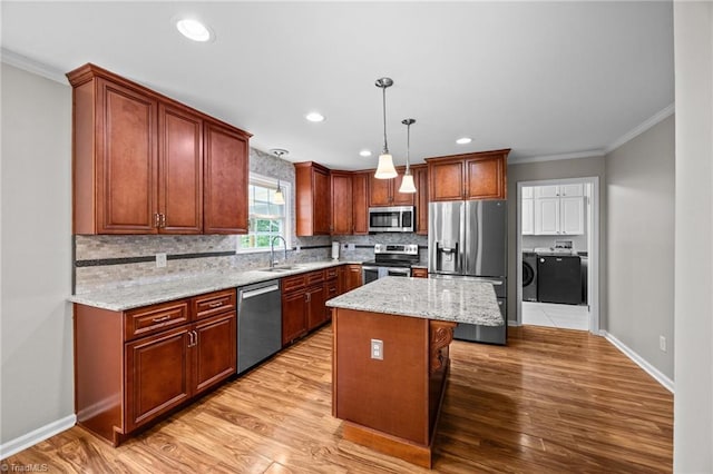 kitchen featuring crown molding, baseboards, washing machine and clothes dryer, appliances with stainless steel finishes, and backsplash