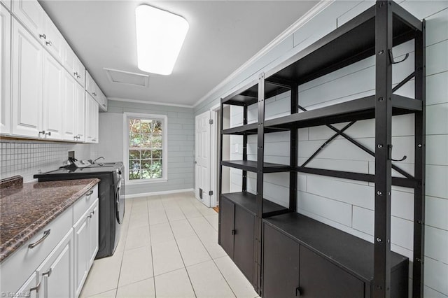 laundry room with ornamental molding, attic access, washing machine and clothes dryer, cabinet space, and light tile patterned floors