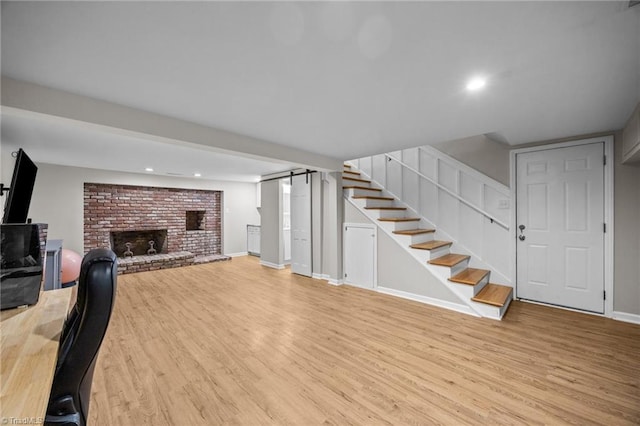 living area featuring stairs, recessed lighting, light wood-style flooring, and a fireplace