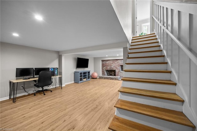 stairs featuring baseboards, recessed lighting, wood finished floors, and a fireplace
