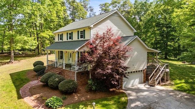 view of front of house with a front lawn, covered porch, stairs, an attached garage, and driveway