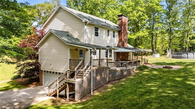 rear view of property featuring a garage, a chimney, a lawn, an outdoor fire pit, and stairway